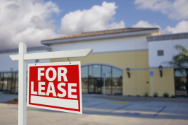 Vacant Retail Building with For Lease Real Estate Sign in Front.